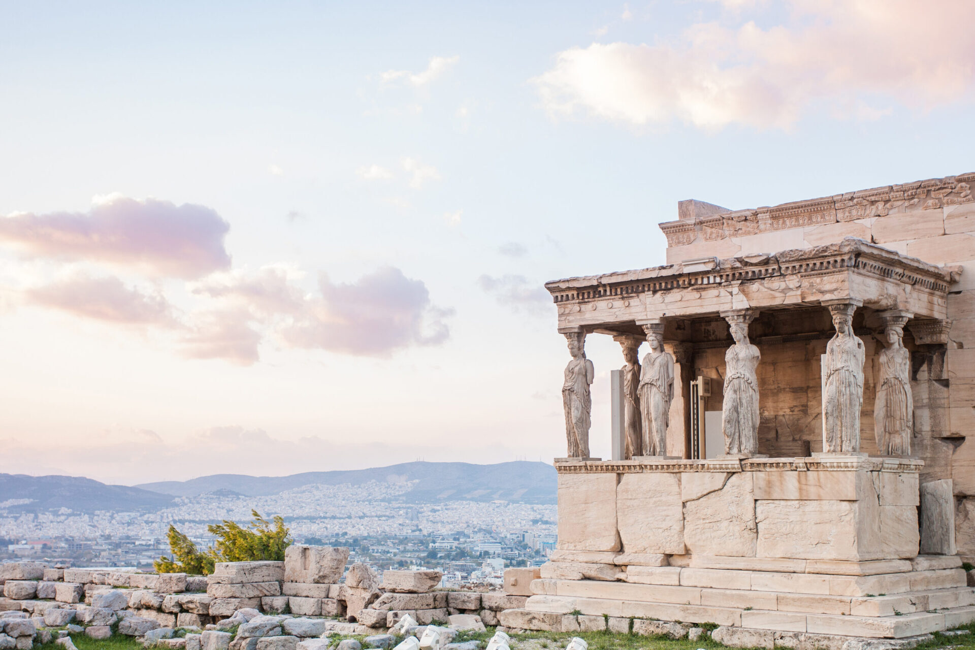The Caryatids of Erechtheion on the sacred Acropolis rock against cotton candy skies of Athens, one of the best places to travel in January.