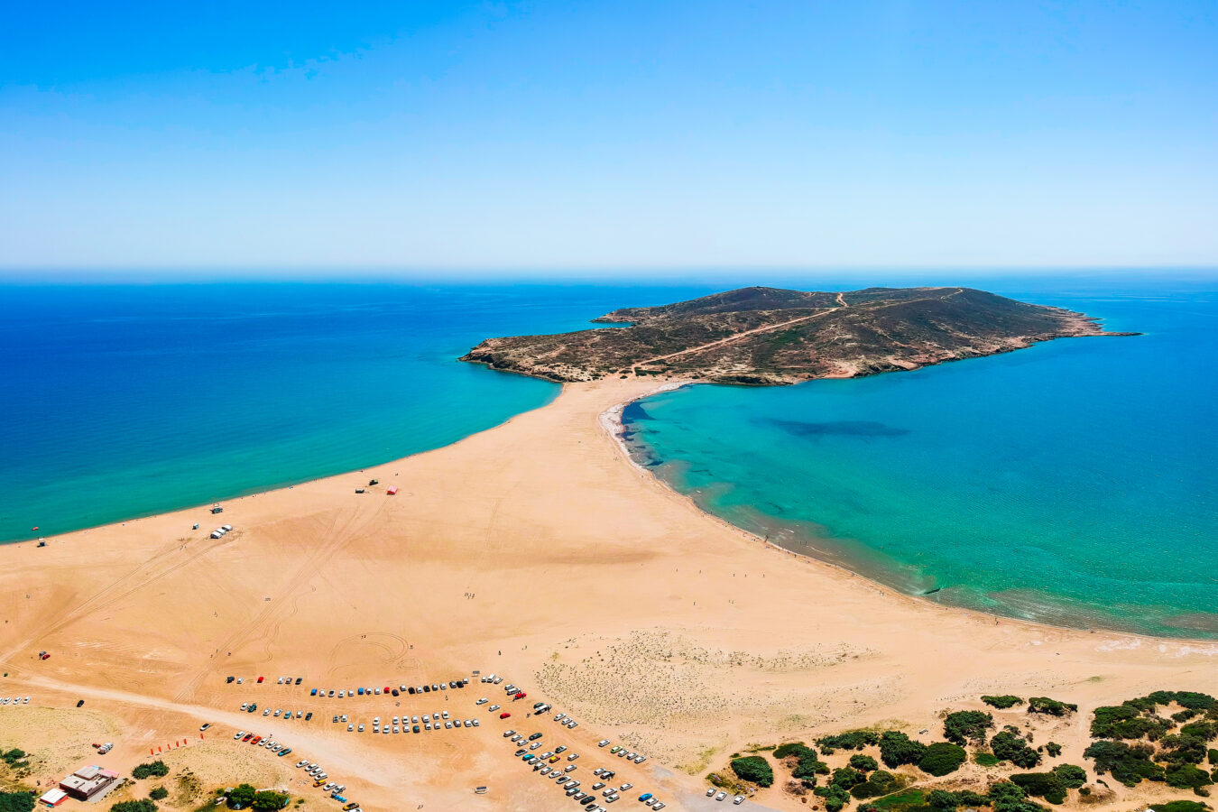 View across Prasonisi Beach towards the rocky islet, showing the changing sandy connection between the Aegean and Mediterranean seas.